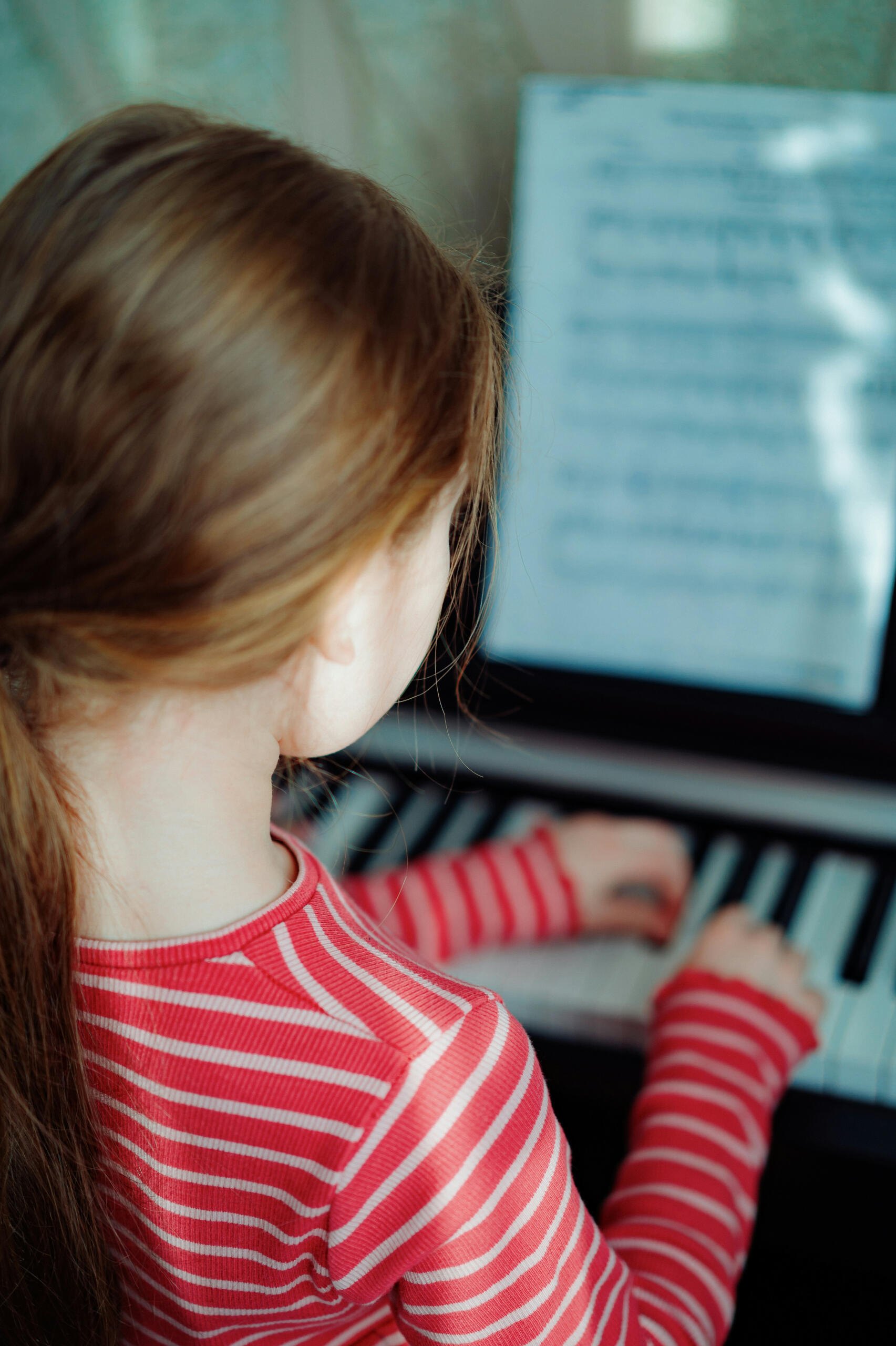 A little girl playing piano with sheet music in the foreground. Stittsville Kanata Piano Lessons.